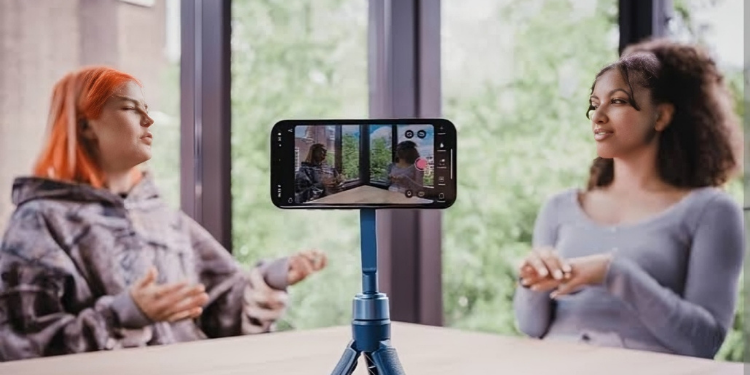 A photo of two creaters recording a podcast using a phone. PHOTO/ Detail.