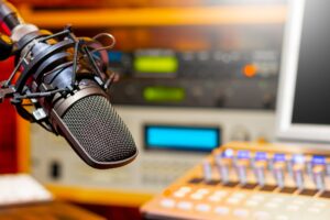 The Image Displays Professional Recording Equipment, Specifically a Microphone and a Mixing Console Within a Radio or Podcast Studio. PHOTO/ COURTESY 