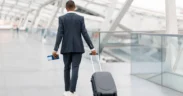 Black Man In Suit Walking With Suitcase At Airport Terminal. PHOTO/ Courtesy
