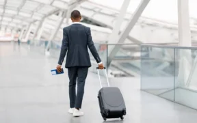 Black Man In Suit Walking With Suitcase At Airport Terminal. PHOTO/ Courtesy
