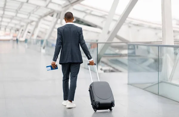 Black Man In Suit Walking With Suitcase At Airport Terminal. PHOTO/ Courtesy