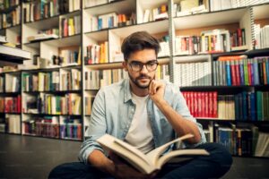 This Image Shows a Man Reading a Book While Sitting on the Floor of a Library. PHOTO/ Courtesy 