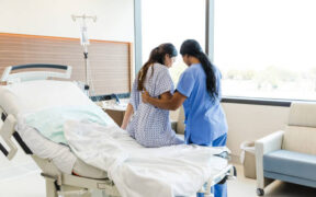 An Unrecognizable Female Nurse Helps the Unrecognizable Woman Get out of the Hospital Bed. PHOTO/ Courtesy