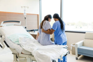 An Unrecognizable Female Nurse Helps the Unrecognizable Woman Get out of the Hospital Bed. PHOTO/ Courtesy