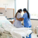 An Unrecognizable Female Nurse Helps the Unrecognizable Woman Get out of the Hospital Bed. PHOTO/ Courtesy