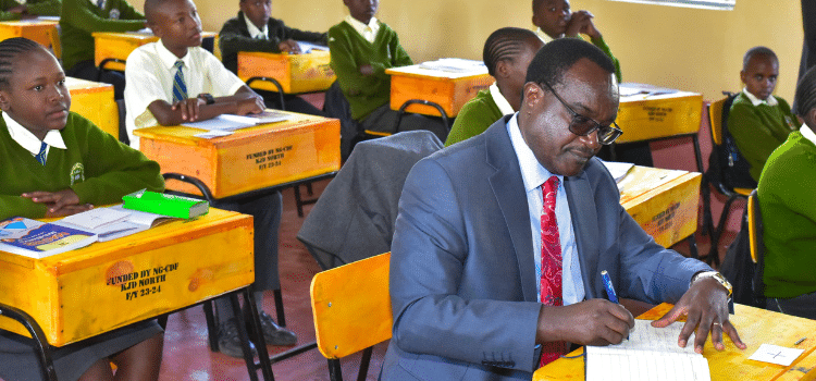 Education CS Julius Ogambo sitting in a classroom. PHOTO/NA