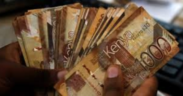 A hand holding Kenyan 1,000-shilling notes