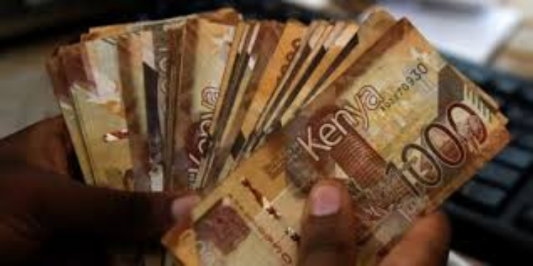 A hand holding Kenyan 1,000-shilling notes
