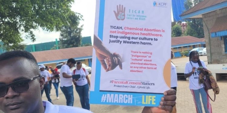 A participant in the 2026 KCPF "March for Life" holds a placard in Nairobi, challenging the framing of medical abortion as "indigenous healthcare." The march concluded a week-long advocacy campaign by Kenyan Christian professionals aimed at protecting the dignity of the pre-born. PHOTO/ Uhondo Media X