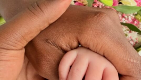 Apicture of Betty Kyalo and Charlie holding their baby's hand