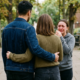 AI Image of a man embracing a woman from behind while another woman stands facing them in tears, creating a dramatic, emotional scene.