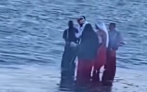 A group dressed in unusual red, black and white attire spotted carrying chickens along Diani Beach. PHOTO/ SCREENGRAB.