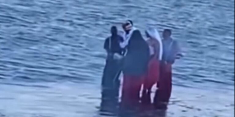 A group dressed in unusual red, black and white attire spotted carrying chickens along Diani Beach. PHOTO/ SCREENGRAB.