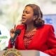 A photo of the Chief Executive Officer of Kenya's Social Health Authority (SHA) Dr. Mercy Mwangangi delivering a national COVID-19 update at Afya House during the pandemic during her tenure as the Chief Administrative Secretary (CAS) for the Ministry of Health in Kenya and an insert of SHA logo. PHOTO/ MoH Facebook/ SHA